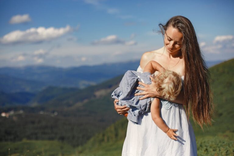 A loving mother cradles her child against a scenic mountain backdrop.
