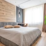 A clean and bright modern bedroom featuring wooden accents, neutral tones, and a potted plant.