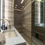 A contemporary bathroom featuring sleek marble surfaces, elegant fixtures, and ambient lighting.