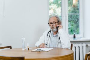 A senior doctor making a telemedicine call in an office setting, discussing medical cases.