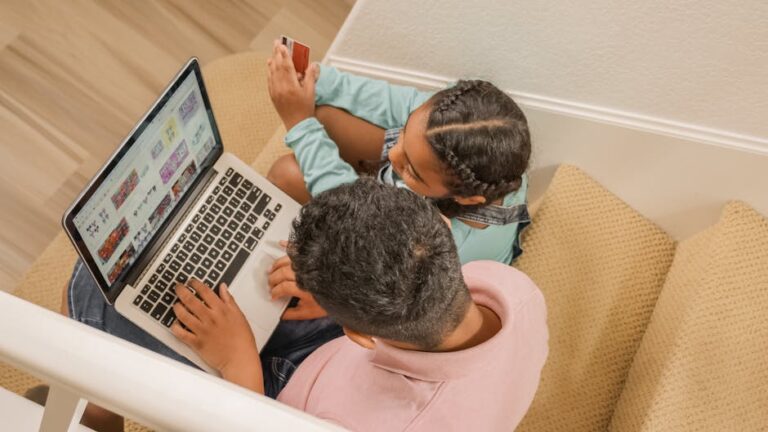 A father and daughter sit on stairs, engaging in online shopping together using a laptop.