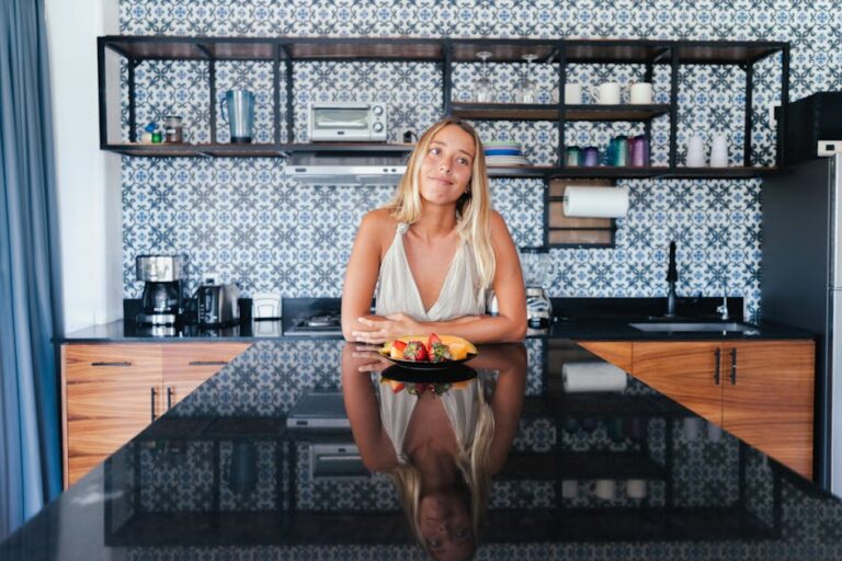 Woman in kitchen smiling over healthy breakfast plate, showcasing modern interior design