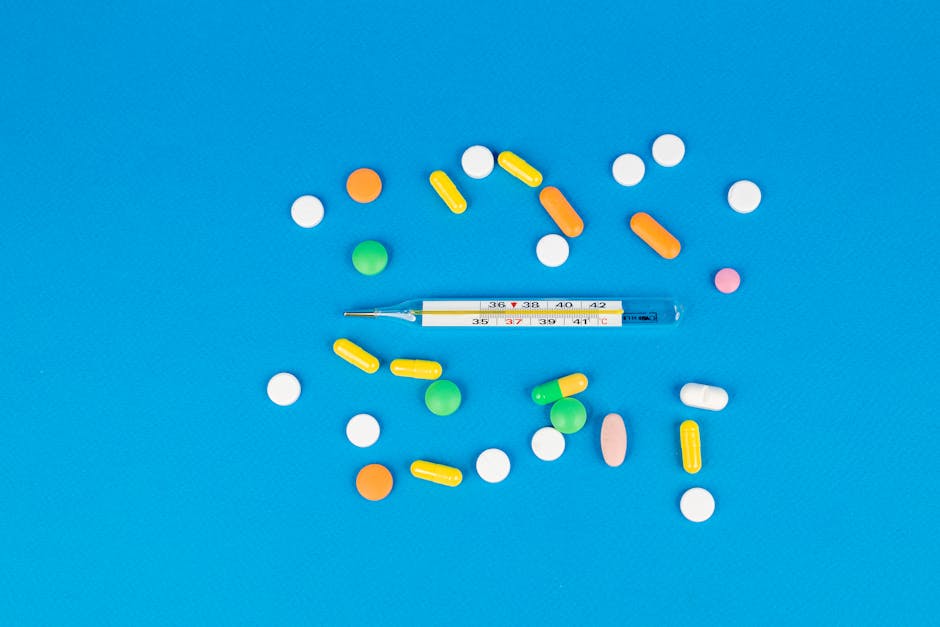 Vibrant pills and a thermometer arranged on a blue backdrop. Perfect for health and medicine themes.