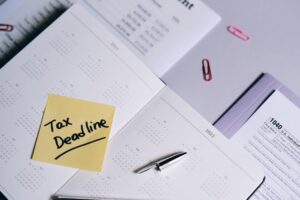 A calendar with a tax deadline note and tax forms, emphasizing organization.