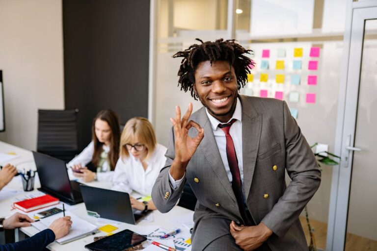 Smiling businessman signaling OK, working with diverse team in modern office.