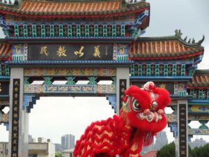 Vivid red dragon costume in front of a traditional Chinese temple gate during daytime.