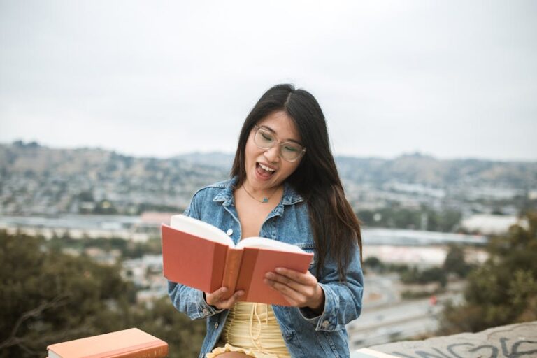 Young woman in a denim jacket enjoys reading a book outdoors.