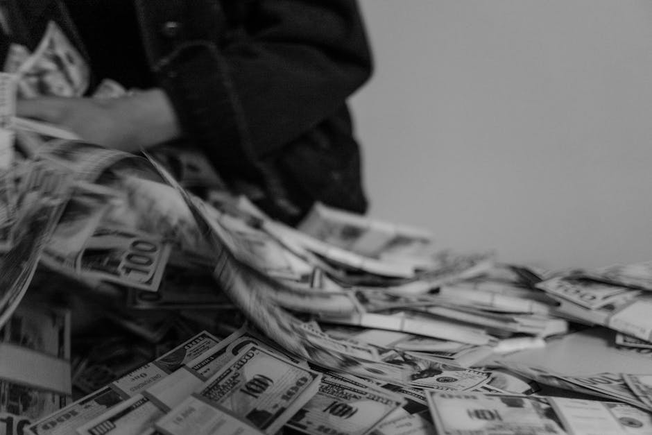 A blur of hands moving through a pile of US dollar bills, captured in black and white.