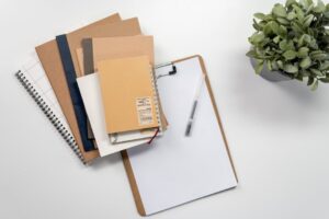 A flat lay of notepads, clipboards, and pens in a minimalist home office setting